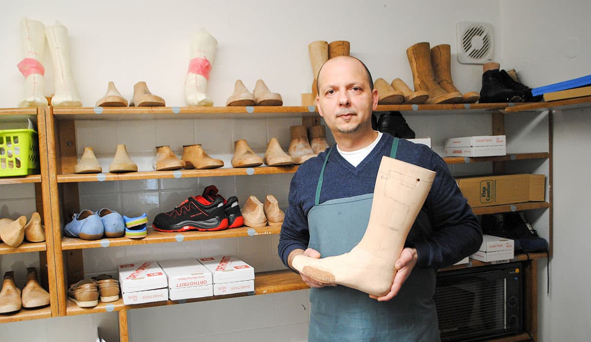 Orthopädieschuhtechnik-Meister Sebastijan Ismailov mit einem Schuhleisten in der Werkstatt